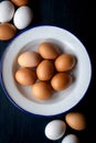 Fresh brown and white eggs in an enamel bowl on rustic wood background with copy space. Top view. Royalty Free Stock Photo