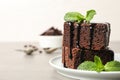 Fresh brownies with sauce and mint on table