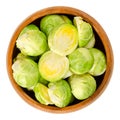 Fresh Brussels sprouts in wooden bowl over white