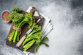 Fresh bunch of Broccolini sprouts on cutting board ready for cookining. White background. Top view. Copy space