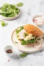 Fresh burger with scrambled eggs, spinach, radish slices on white marble kitchen table for breakfast Royalty Free Stock Photo