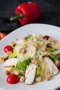 Fresh caesar salad with chicken on a white plate on dark stone background. Flat lay with ingridients for cook. Royalty Free Stock Photo