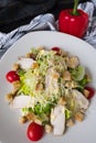 Fresh caesar salad with chicken on a white plate on dark stone background. Flat lay with ingridients for cook. Royalty Free Stock Photo