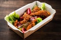 fresh caesar salad with fried chicken meat in paper take away container on wooden table Royalty Free Stock Photo