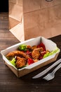 fresh caesar salad with fried chicken meat in paper take away container on wooden table Royalty Free Stock Photo