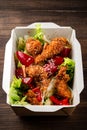 fresh caesar salad with fried chicken meat in paper take away container on wooden table Royalty Free Stock Photo