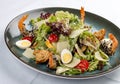 Fresh caesar salad on white bowl with parmesan cheese and shrimps. In a decorative plate Royalty Free Stock Photo