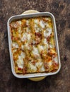 Fresh cannelloni pasta with spinach and ricotta baked with mozzarella cheese in a baking dish on a wooden background, top view Royalty Free Stock Photo