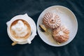 Fresh cappuccino art with plate with tasty cakes.