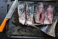 Fresh carp on a dark background with greens and vegetables. Cut into pieces carp on a wooden board Royalty Free Stock Photo