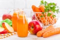 Fresh carrot and apple juice on white background. Carrot and apple juice in glass bottles on white table, closeup Royalty Free Stock Photo