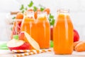 Fresh carrot and apple juice on white background. Carrot and apple juice in glass bottles on white table, closeup Royalty Free Stock Photo