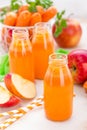 Fresh carrot and apple juice on white background. Carrot and apple juice in glass bottles on white table, closeup Royalty Free Stock Photo