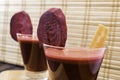 Fresh carrot and beetroot juice in glass decorated with carrot and beetroot slices on wooden tray and bamboo background selective Royalty Free Stock Photo