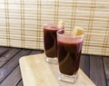 Fresh carrot and beetroot juice in glass decorated with carrot slices on wooden tray and bamboo background selective focus toned Royalty Free Stock Photo