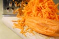 Fresh carrot grated on a metal kitchen grate. Vegetables prepared for salad with a meal on the kitchen table