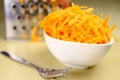 Fresh carrot grated on a metal kitchen grate. Vegetables prepared for salad with a meal on the kitchen table