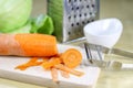 Fresh carrot grated on a metal kitchen grate. Vegetables prepared for salad with a meal on the kitchen table