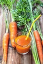 Fresh carrot juice in glass on a brown wooden background.