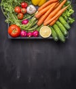 Fresh carrots cherry tomatoes, garlic, cucumber, lemon, pepper, radish, wooden spoon salt pepper colored, oil wooden rustic backgr Royalty Free Stock Photo