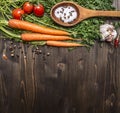 Fresh carrots with cherry tomatoes, garlic and wooden spoon vintage salt and pepper colored it wooden rustic background top vie Royalty Free Stock Photo