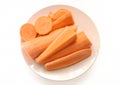 Fresh carrots, cut into pieces, lie on a round plate, top view