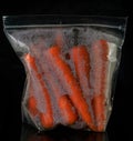 Fresh carrots in a plastic bag isolated on black background. - image