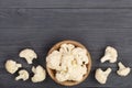 Fresh cauliflower cut into small pieces in wooden bowl on black background with copy space for your text. Top view Royalty Free Stock Photo