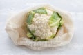 Fresh cauliflower with reusable bag on ceramic background