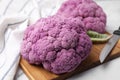 Fresh cauliflowers, cutting board and knife on white table, closeup