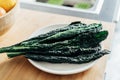 Fresh Cavolo Nero kale leaves on a white plate and on rustic wooden background on the kintchen table. Healthy eating Royalty Free Stock Photo