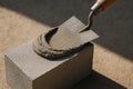 Fresh cement applied on a concrete block with a trowel under sunlight, showcasing masonry construction process and building Royalty Free Stock Photo