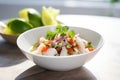 fresh ceviche in a white bowl with lime wedges and cilantro