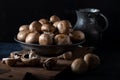 Fresh champignon button mushrooms in bowl on a wooden board front of the dark background