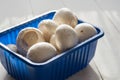 Fresh champignons in blue box on white wooden background. Close-up Royalty Free Stock Photo