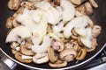 Fresh champignons and onions are fried in a pan. Top view