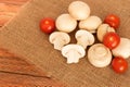 Fresh mushrooms champignons and tomatoes in bulk lie on a natural fabric.