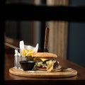 Fresh cheeseburger prepared by chef. Fast food menu with burger, fried potatoes and sauce on wooden board. Nutritious Royalty Free Stock Photo
