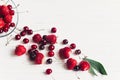 fresh cherries and strawberries scattered from bowl on white rustic wooden background. ripe juicy red berries on table, harvest Royalty Free Stock Photo