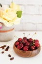 Fresh cherries in a wooden bamboo bowl. Bright Brick Wall Background. Yellow Roses in a Vase. Healthy Lifestyle Concept. Copy Spac Royalty Free Stock Photo