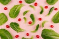 Fresh cherry tomato and leaves spinach on soft gentle pink background, pattern, cheerful modern spring food backdrop.