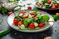 Fresh Cherry Tomato, Mozzarella salad with green lettuce mix and red onion. served on plate. healthy food. Royalty Free Stock Photo