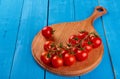 Fresh cherry tomatoes on a branch on a wooden cutting board on blue wooden rustic background top view Royalty Free Stock Photo