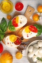 Fresh cherry tomatoes, mozzarella cheese and tasty sandwiches on wooden table, top view Royalty Free Stock Photo