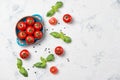 Fresh cherry tomatoes on a plate, basil leaves and black pepper on stone table, top view Royalty Free Stock Photo