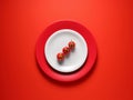 Fresh cherry tomatoes on a plate with red background. Top view, copy space. Creative food concept Royalty Free Stock Photo