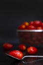 Fresh cherry tomatoes on a silver spoon placed on the table with water drops and a blur tomato basket background. Food photo Royalty Free Stock Photo