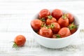 Fresh cherry tomatoes in white ceramic bowl on rustic wooden background. Soft focus. Royalty Free Stock Photo