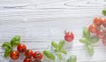 Fresh cherry tomatoes on white  wooden background. Tomato red vegetable concept, copy space for text with basil leaves Royalty Free Stock Photo