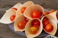 Fresh cherry tomatoes in wooden cones on a purple plate, ideal for organic food markets...Fresh cherry tomatoes in wooden cones on Royalty Free Stock Photo